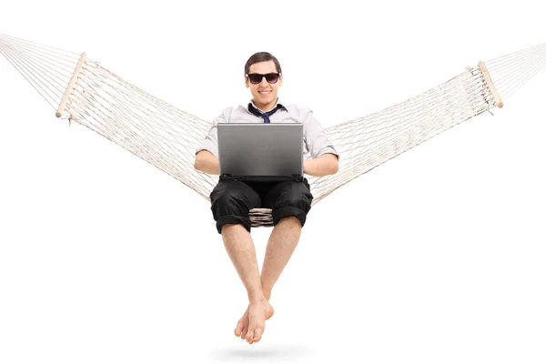 Zakenman zittend op een hangmat en die op laptop werkt — Stockfoto