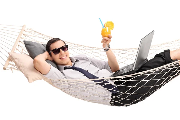 Бизнесмен лежит в гамаке и пьет коктейль — стоковое фото