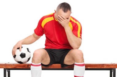 bir bankta oturan endişeli futbolcu
