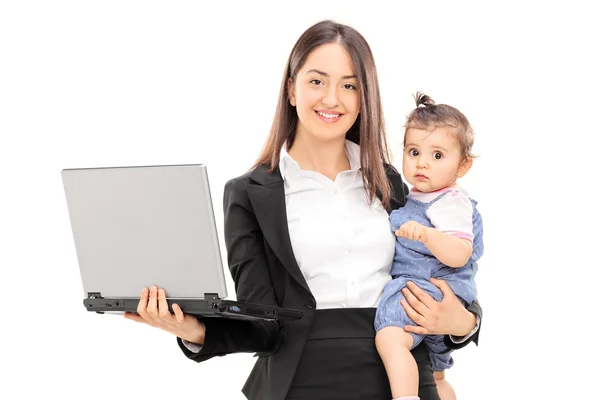 Empresária carregando sua filha e segurando um laptop — Fotografia de Stock