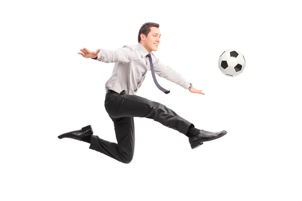 Young businessman kicking a football and smiling — Stok fotoğraf