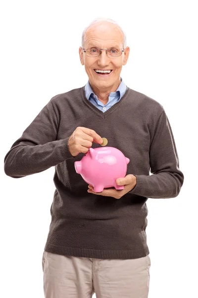 Hombre mayor poniendo moneda en una hucha —  Fotos de Stock