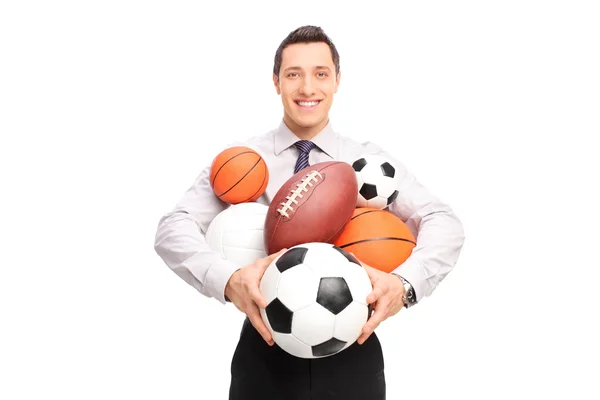 Человек, держащий кучу спортивных мячей — стоковое фото