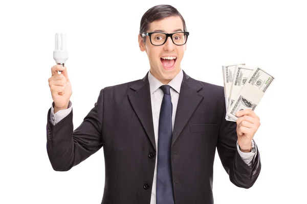 Бизнесмен держит лампочку и деньги — стоковое фото