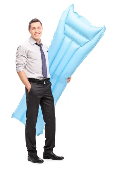 Бизнесмен держит синий плавательный матрас — стоковое фото