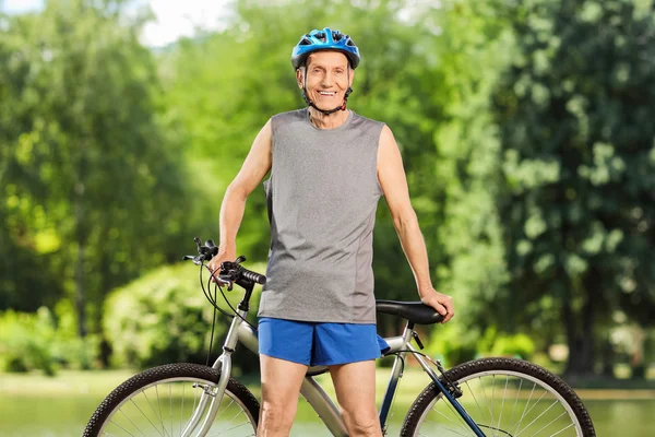 Motociclista senior apoyado en su bicicleta y posando al aire libre — Foto de Stock