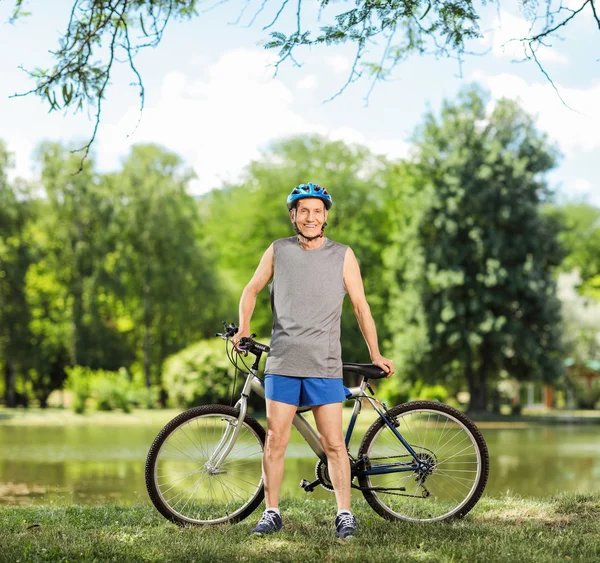 Senior cyclist posing by a pond in a park