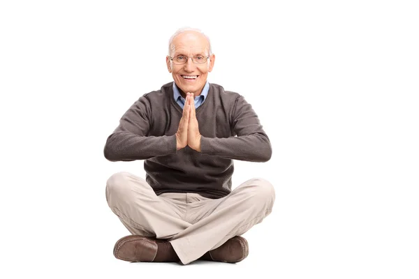 Senior gentleman meditating seated on the floor — Stockfoto