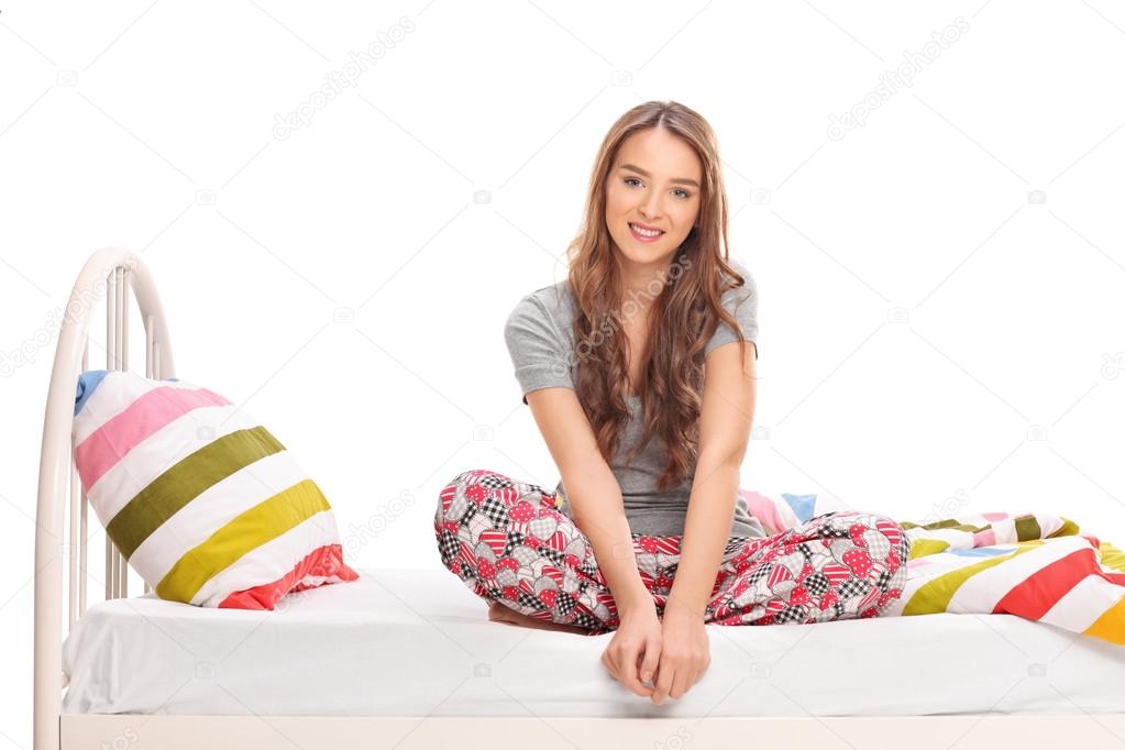 Beautiful brunette woman sitting on a bed 