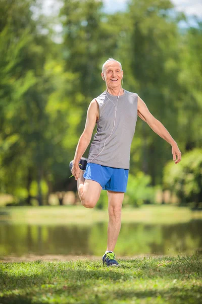 Joyeux senior étirant ses jambes dans un parc — Photo