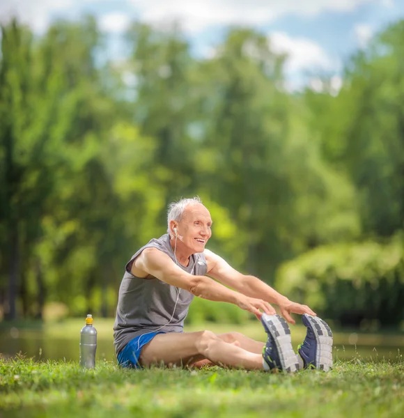 Senior doing stretching exercises in park — 图库照片