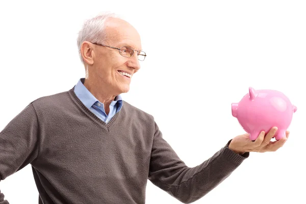 Studio shot of a senior smiling at a piggybank — Stockfoto