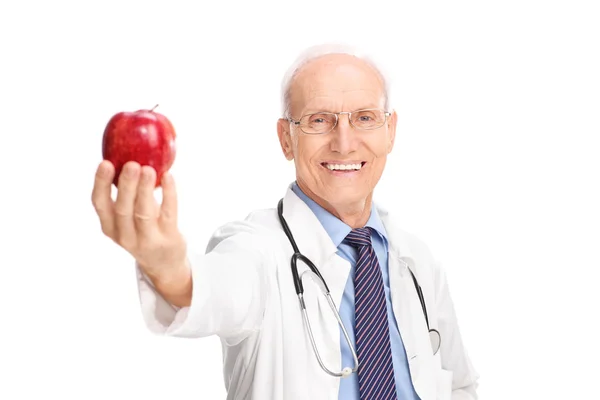 Cheerful mature doctor holding a red apple — Stock Photo, Image