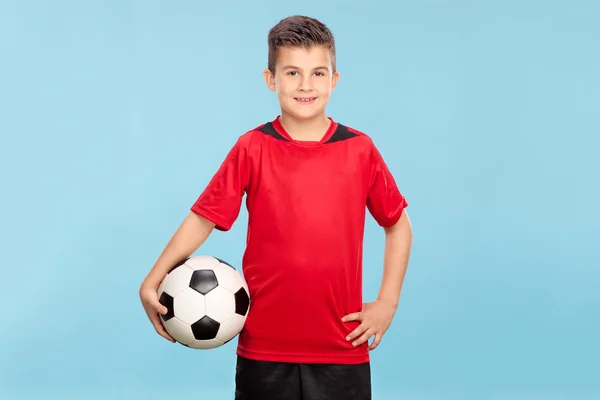 Menino em uma camisa vermelha segurando uma bola de futebol — Fotografia de Stock