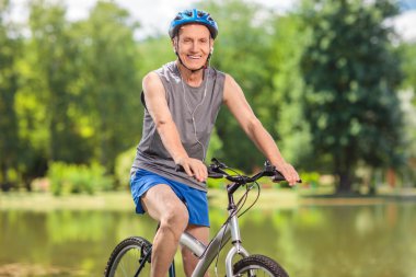Senior biker with a blue helmet posing on his bicycle