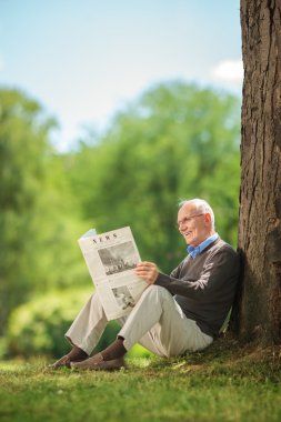Senior man reading a newspaper in park 