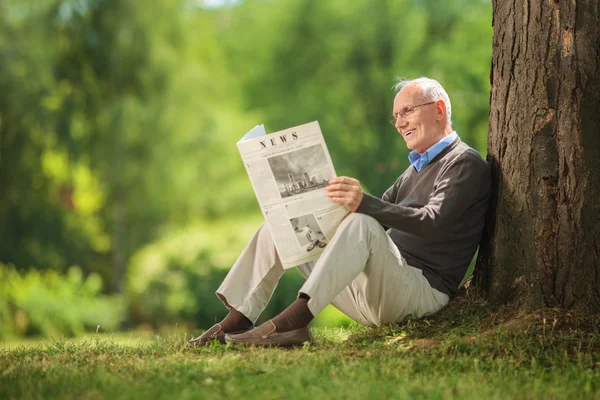Pria senior membaca koran di taman — Stok Foto