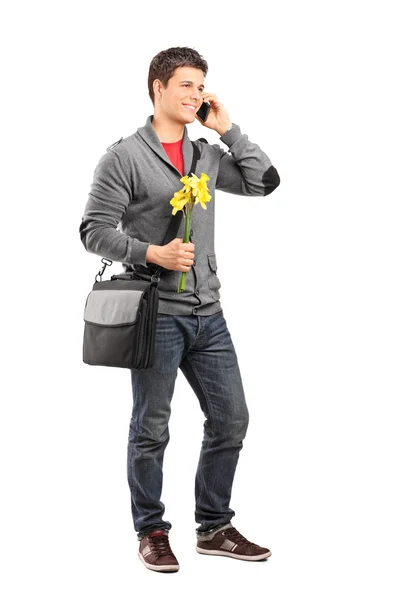 Молодой человек держит цветы и разговаривает по телефону — стоковое фото