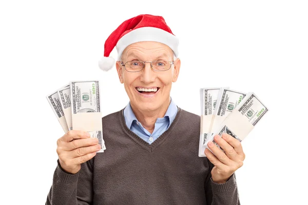 Senior mit Weihnachtsmütze mit sechs Stapeln Geld — Stockfoto