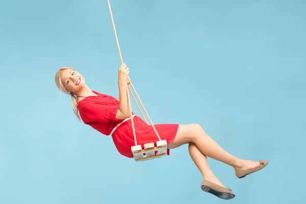 Carefree blond woman swinging on a swing — Stockfoto