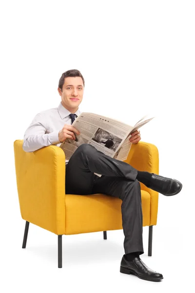 Man in armchair holding a newspaper — 图库照片