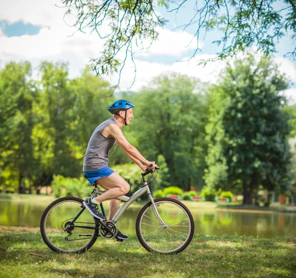 Ciclista senior montando una bicicleta en un parque — Foto de Stock