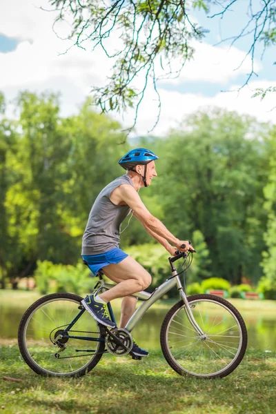 Senior man riding a bicycle in a park — ストック写真