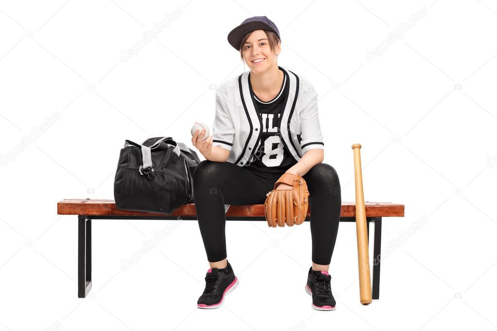 Female athlete holding a baseball on bench