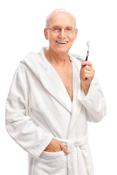 Старший чоловік у халаті, що тримає зубну щітку — стокове фото