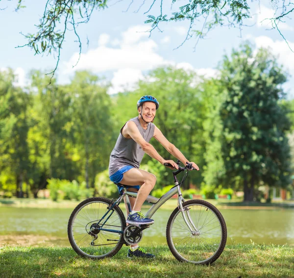 Motociclista senior montando una bicicleta en el parque —  Fotos de Stock