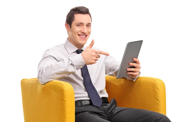 Businessman holding a tablet seated in an armchair — Stok fotoğraf