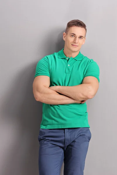 Young man leaning against a gray wall — Stok fotoğraf