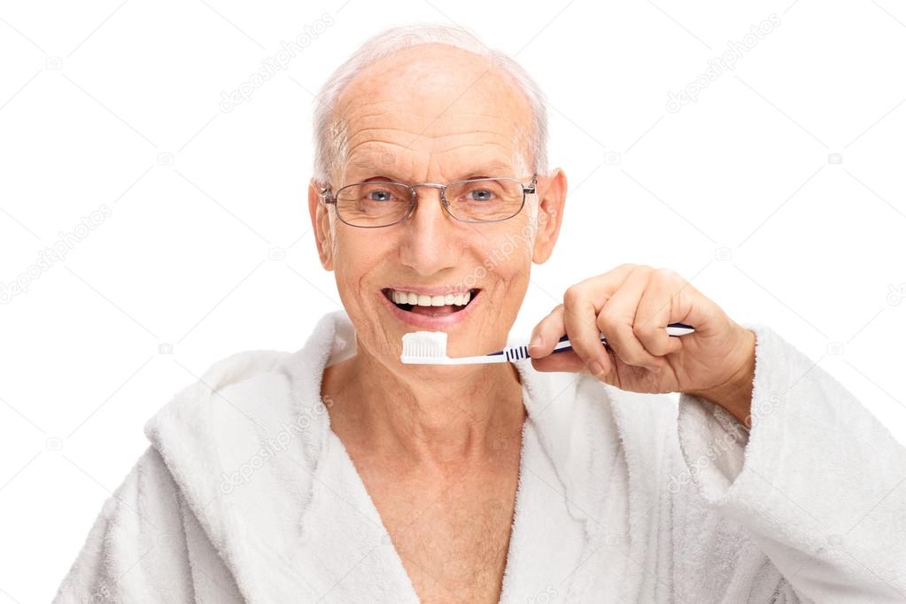Cheerful senior man brushing his teeth
