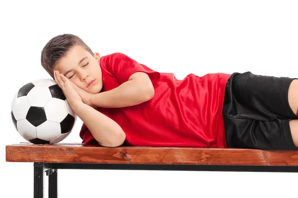 Ragazzo in uniforme da calcio che dorme sulla panchina — Foto Stock