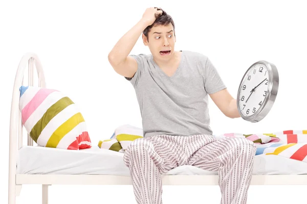 Hombre sorprendido sentado en una cama en pijama — Foto de Stock