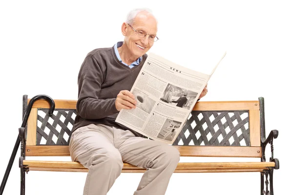 Homem sénior lendo um jornal em um banco — Fotografia de Stock