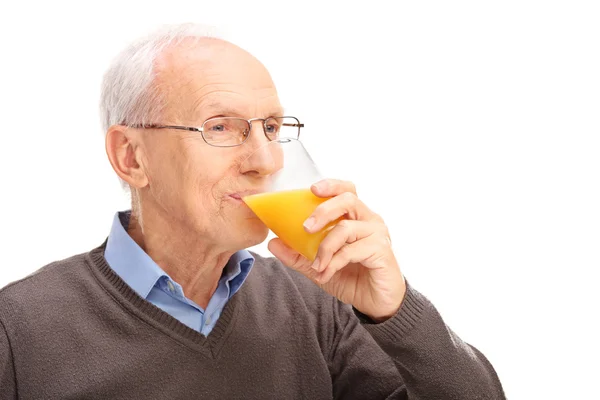 Senior man drinking an orange juice — Stock Photo, Image