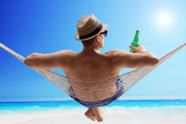 Relaxed guy in a hammock drinking beer — Stock Photo, Image