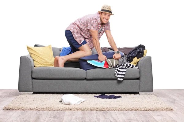 Человек упаковывает одежду в чемодан — стоковое фото