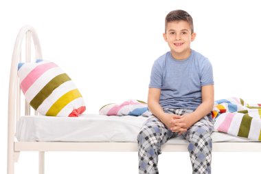 Yatağı üzerinde oturan mavi pijama boy