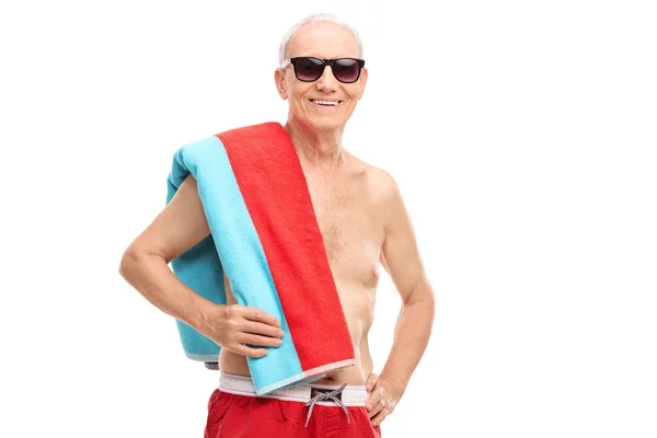 Mature tourist in swim trunks holding a towel — Stock Photo, Image