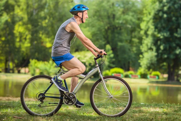 Senior biker riding a bicycle in a park — Stock Photo, Image