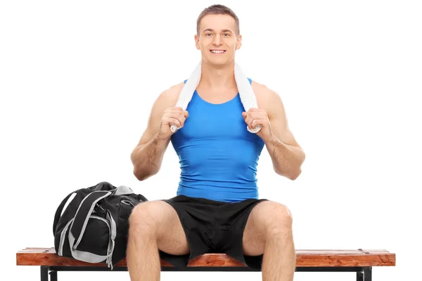 Young athlete seated on a wooden bench — Stock Photo, Image