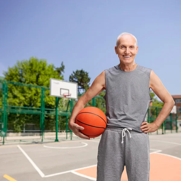 Старший мужчина в спортивной одежде держит баскетбол — стоковое фото