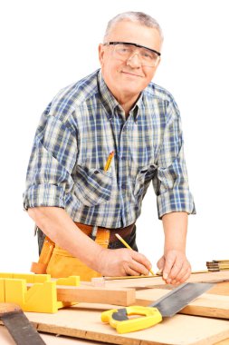 Mature carpenter measuring a plank clipart