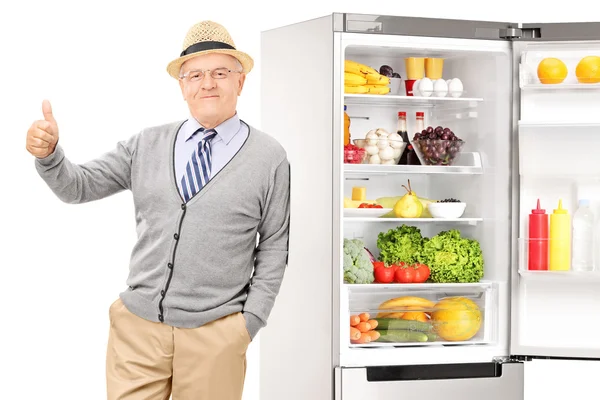 Äldre man lutar på kylskåp — Stockfoto