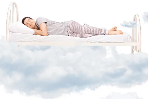 Young man sleeping on bed in clouds — Stock Photo, Image