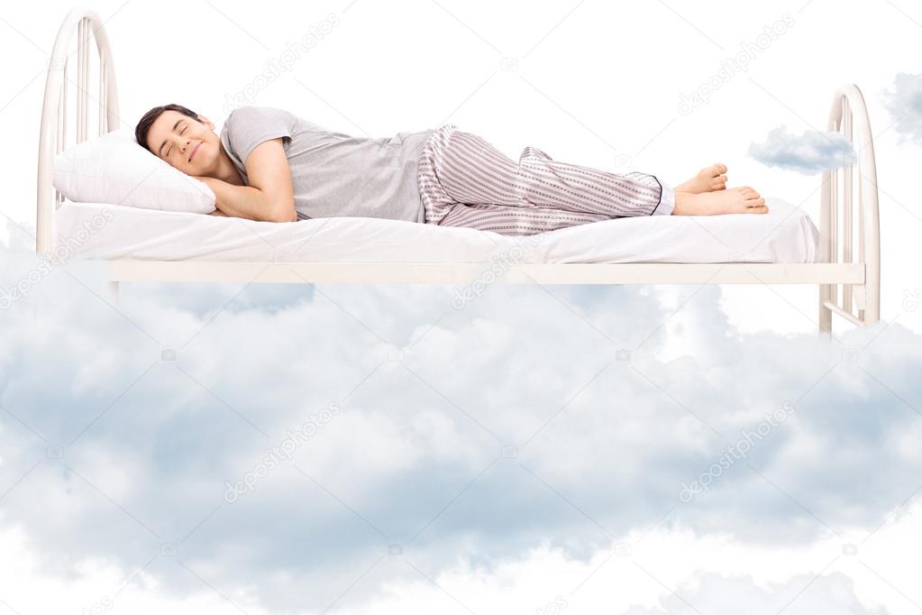 Young man sleeping on bed in clouds