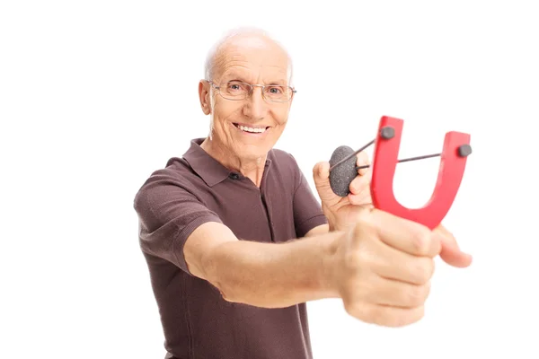 Cheerful senior man shooting a slingshot — Stock Photo, Image