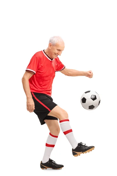 Senior im roten Trikot jongliert mit einem Fußball — Stockfoto